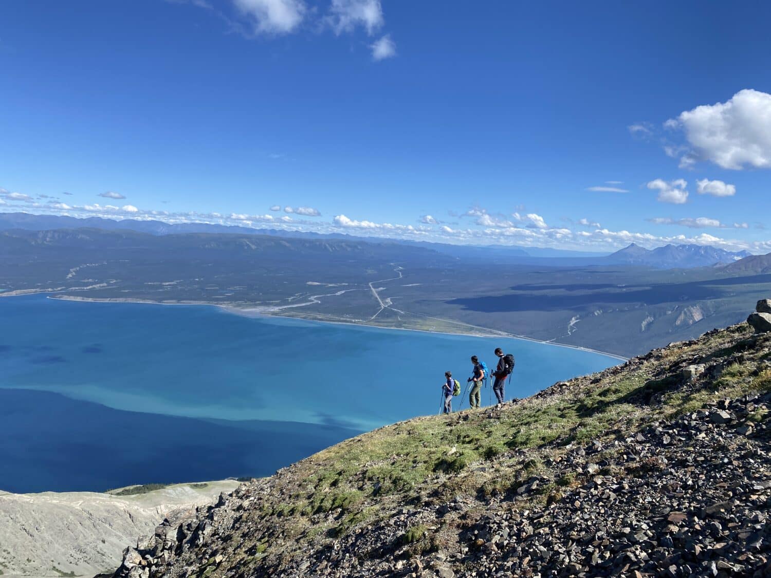 Hikers along the ridge of Sheep mountain looking down at Kluane Lake