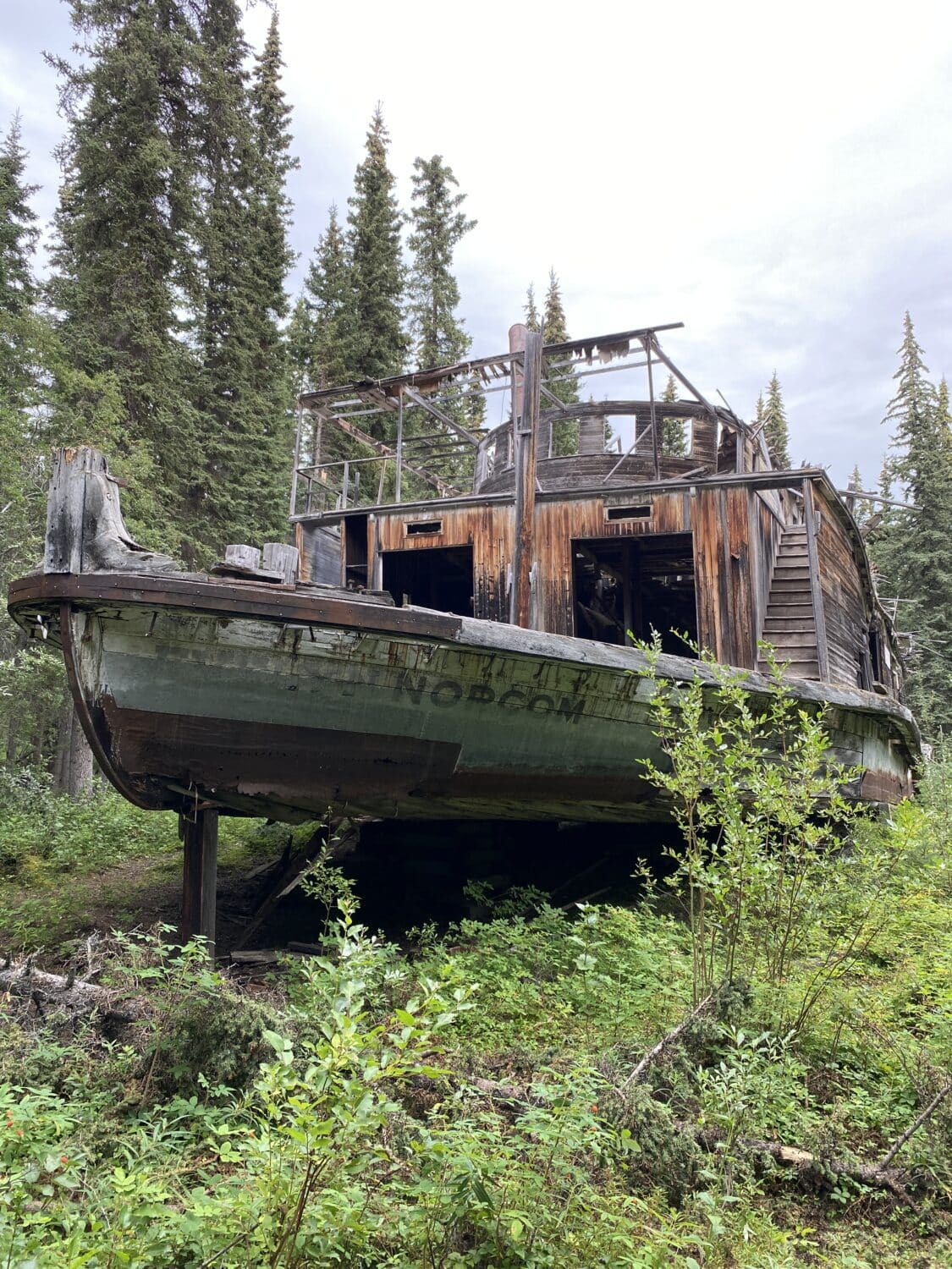 Abandoned boat in forested area.